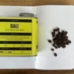 Rich coffee beans and a coffee tasting sheet from Bali, Catur Region, showcasing single origin coffee with notes of caramel, molasses, and dark chocolate, perfect for coffee enthusiasts seeking premium brews.
