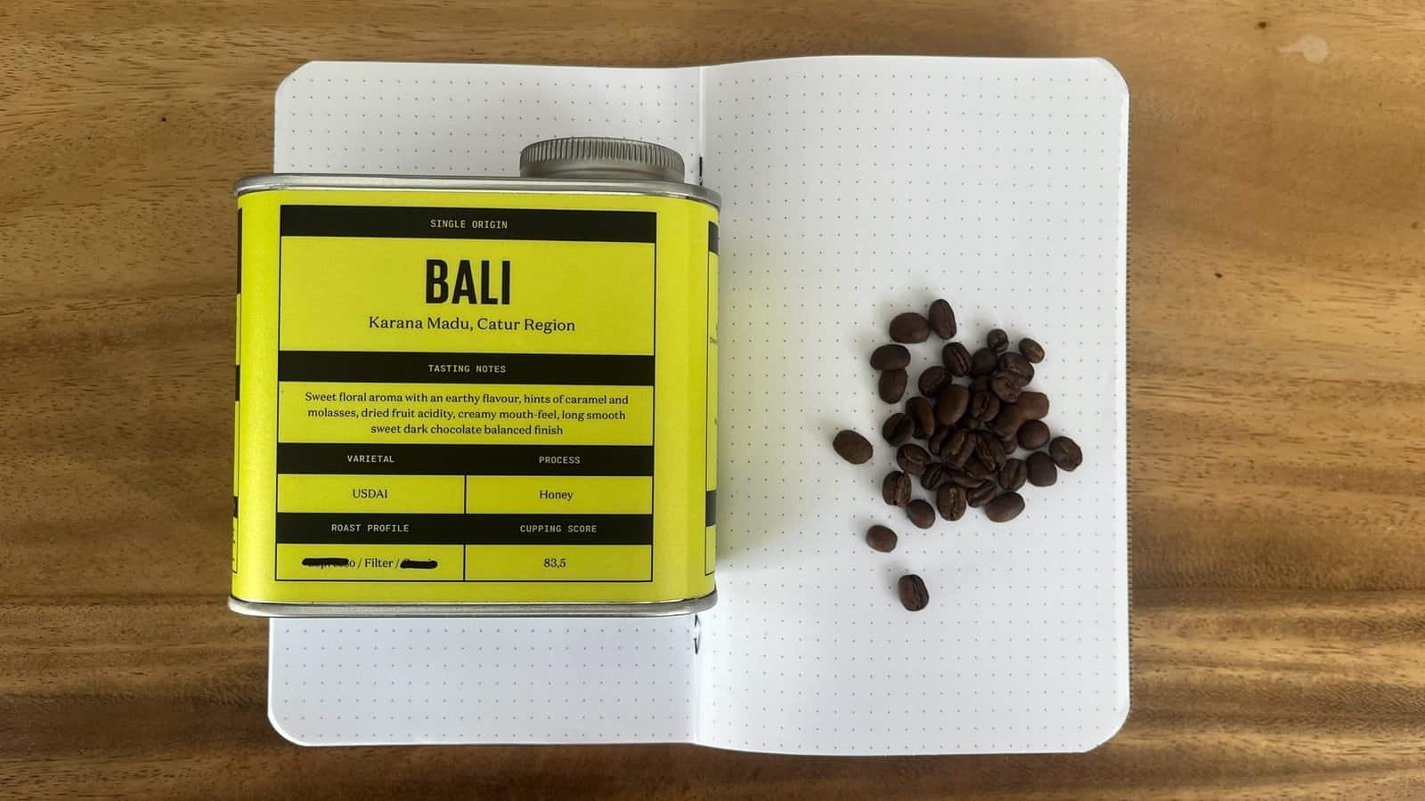 Rich coffee beans and a coffee tasting sheet from Bali, Catur Region, showcasing single origin coffee with notes of caramel, molasses, and dark chocolate, perfect for coffee enthusiasts seeking premium brews.