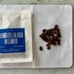 Roasted coffee beans on dotted notebook page with Indonesian coffee packaging, close-up.