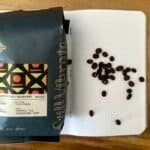 Rich coffee beans from Cuarenteño Peaberry Mexico, on a notebook with scattered beans, showcasing premium quality coffee aligned with Barnaby Robson's coffee expertise.