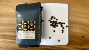 Rich coffee beans from Cuarenteño Peaberry Mexico, on a notebook with scattered beans, showcasing premium quality coffee aligned with Barnaby Robson's coffee expertise.