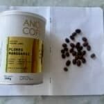 Rich, dark coffee beans on a white dotted notebook page with a cylindrical coffee canister, representing premium coffee quality and brewing expertise.