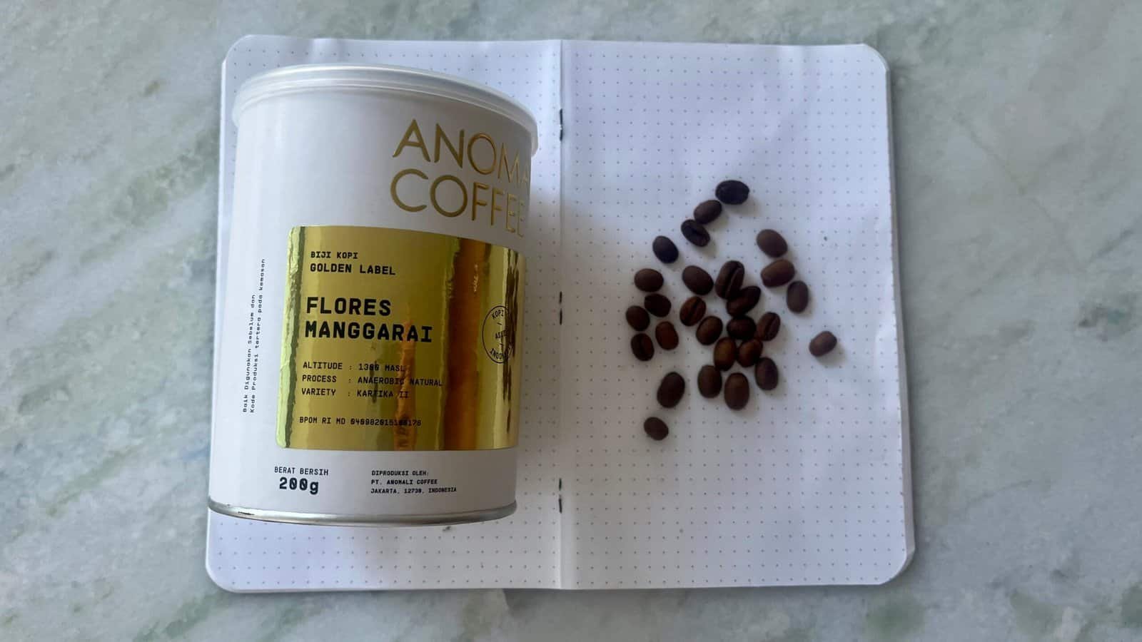 Rich, dark coffee beans on a white dotted notebook page with a cylindrical coffee canister, representing premium coffee quality and brewing expertise.