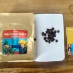 Coffee beans, Gayo Pantan Sinaku, Indonesian single origin coffee, brewing variables card, and packaging on a wooden table.