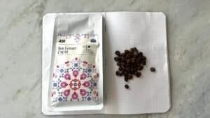 Rich coffee beans and a package of Ijen Lestari CM 91 specialty coffee, on an open dotted notebook, highlighting premium single-origin coffee for connoisseurs.
