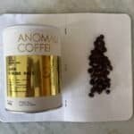 Rich Indonesian coffee beans on a dotted notebook with Anomali Coffee tin, showcasing premium Java Gunung Halu coffee for espresso enthusiasts and coffee connoisseurs.