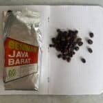 Rich aromatic coffee beans on a dotted notebook page with a packet of Seniman Java Barat coffee, showcasing quality roasted coffee for brewing and espresso lovers.
