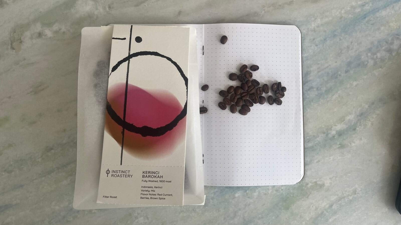 Rich coffee beans on a white dotted notebook with a colourful abstract art card, representing premium coffee and roasting expertise. Perfect for coffee enthusiasts and specialty coffee branding.