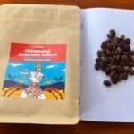 Rich coffee beans on dotted notebook page with herbal supplement packaging and pen, illustrating premium coffee sourcing and natural product quality for Barnaby Robson website.