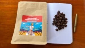 Rich coffee beans on dotted notebook page with herbal supplement packaging and pen, illustrating premium coffee sourcing and natural product quality for Barnaby Robson website.