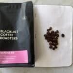 Rich black coffee beans on dotted notebook page with black coffee roast packaging for expert coffee roasting.
