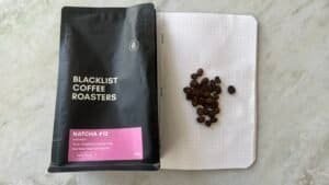 Rich black coffee beans on dotted notebook page with black coffee roast packaging for expert coffee roasting.