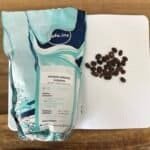 Fresh Arabika Sindoro Sumbing coffee beans on a notebook with a wooden table background, highlighting high-quality single-origin coffee for brewing and tasting enthusiasts.