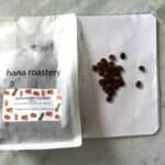 Fresh coffee beans and a coffee packaging bag from Hana Roastery, highlighting premium specialty coffee for roasting and brewing.