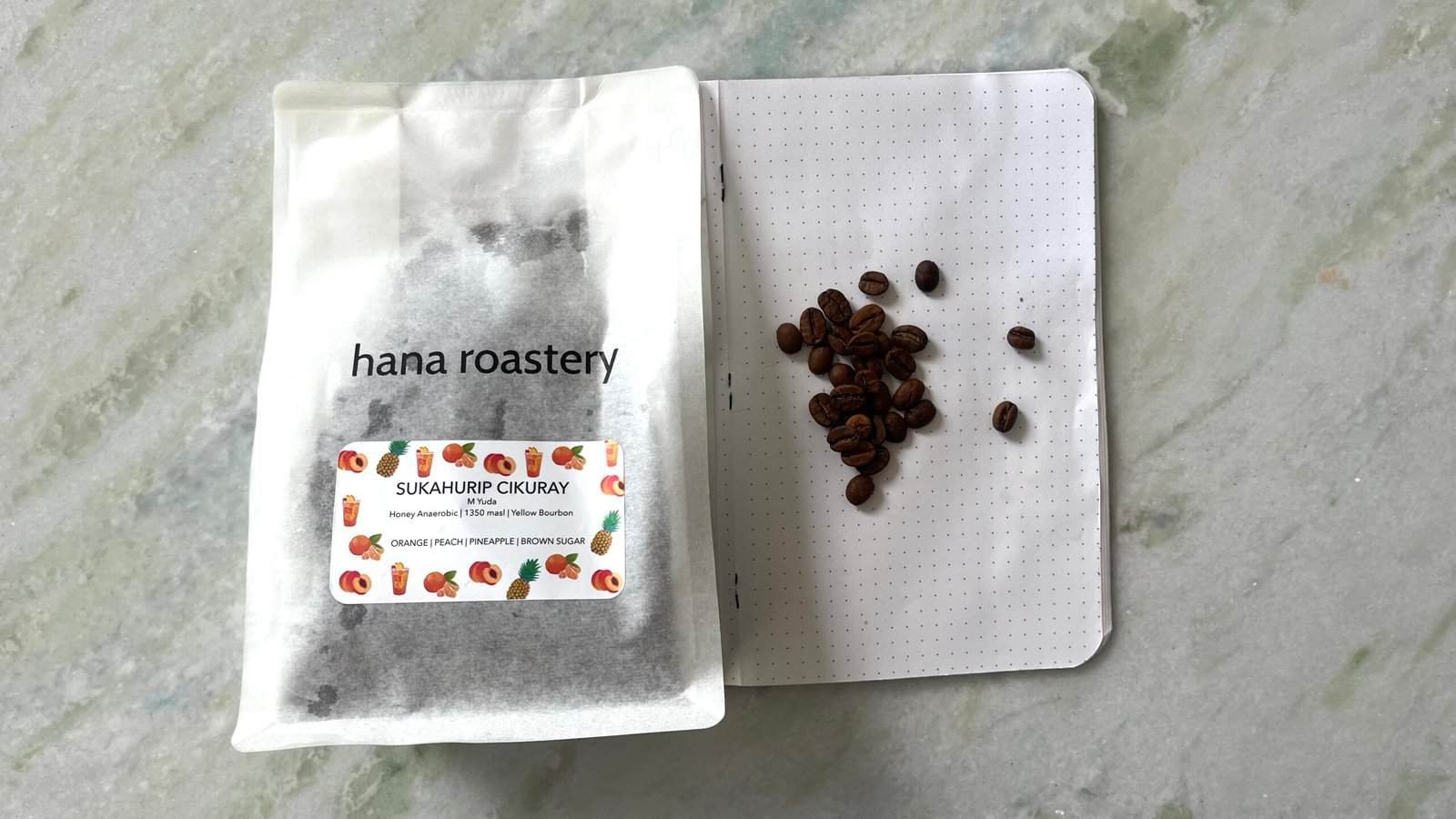 Fresh coffee beans and a coffee packaging bag from Hana Roastery, highlighting premium specialty coffee for roasting and brewing.