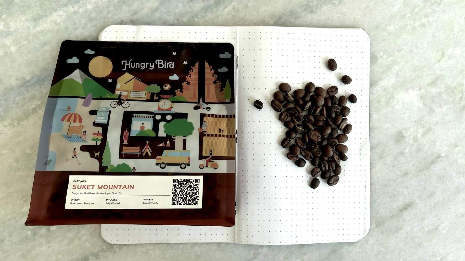 Rich coffee beans on dotted notebook page beside colorful coffee farm map, showcasing premium East Java Suket Mountain coffee, perfect for coffee enthusiasts and lovers of specialty coffee in the UK.