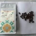 Vegan coffee tasting kit featuring coffee beans, packaging from KOKO, and a notebook with coffee grounds on a grey surface. Perfect for artisanal coffee enthusiasts and sustainable coffee brands.