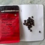 Rich coffee beans from Aceh Gayo Indonesia with brewing notes on a notebook. Coffee lover’s guide to high-quality Arabica beans, featuring Tanamera Coffee Indonesia, showing freshly roasted coffee beans on a textured surface.