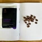 Rich coffee beans scattered on a dotted notebook page with a bag of Toraja Sapan coffee from South Sulawesi, highlighting premium Arabica beans and specialty coffee for connoisseurs.