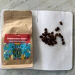 Rich coffee beans and a colourful watermelon smash herbal tea package on a white dotted notebook.