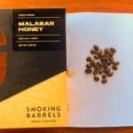 Rich coffee beans and Malabar honey packaging on a wooden table, highlighting craft coffee and premium honey products by Barnaby Robson.