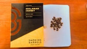 Rich coffee beans and Malabar honey packaging on a wooden table, highlighting craft coffee and premium honey products by Barnaby Robson.